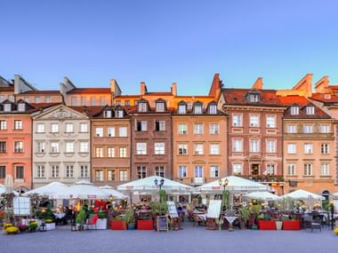 Ein Markt mit vielen Ständen unter quadratischen Sonnenschirmen, vor den Häusern der Altstadt.