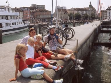Eine Familie macht auf dem Bootssteg eine kleine Pause und lässt die Beine baumeln.
