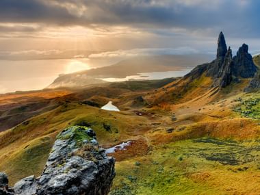 Le coucher de soleil fait briller la mer et le paysage écossais d'un éclat doré.