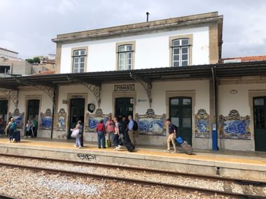 Bahnsteig des Bahnhofs Pinhão mit Reisenden und traditionellen portugiesischen Azulejo-Fliesen mit Douro-Tal-Motiven an den Wänden.