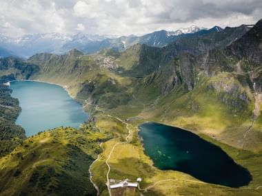 Vue du ciel du lac Ritom, un lac alpin bleu foncé entouré de montagnes vertes et de pics rocheux dans les Alpes suisses.