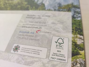 Logo de certification FSC Mix sur une page de catalogue avec paysage montagneux en arrière-plan. Le logo indique du papier de sources responsables.