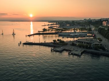Die Sonne geht über dem Lac Léman unter und man sieht den Hafen von Lausanne.