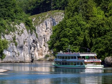Touristenboot namens Weltenburg fährt durch den Donaudurchbruch bei Weltenburg zwischen dramatischen Kalksteinfelsen.