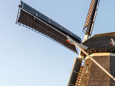 Panoramabild mit der Spitze einer Windmühle vor Wolkenfreiem hellblauen Himmel.