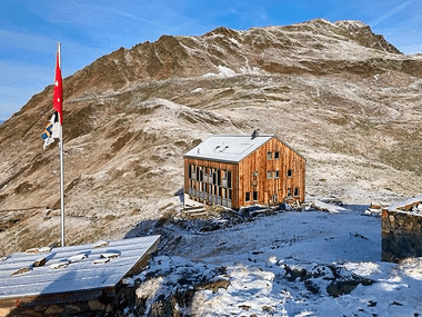 Die Kesch Hütte umgeben von Bergen und Schnee.