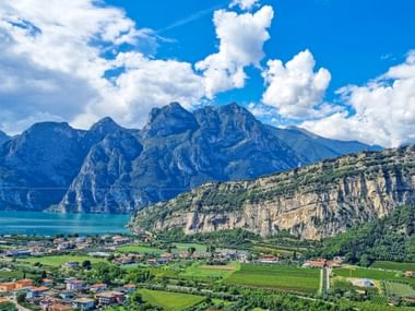 Vue panoramique du lac de Garde avec montagnes spectaculaires, eau turquoise et petite ville nichée entre falaises et vignobles.