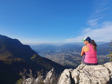 Eine Frau geniesst die Aussicht auf Lugano und Umgebung.