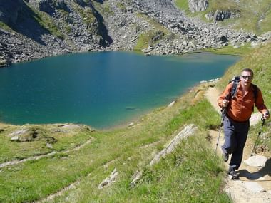 Wanderer auf einem Anstieg auf einen Berg mit kleinem See im Hintergrund