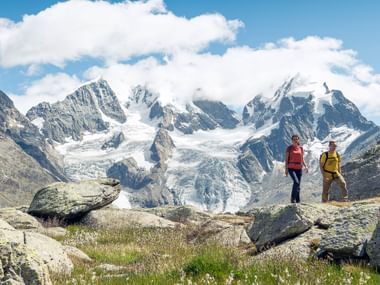 Ein Wanderer Pärchen steht vor einem Schneebedeckten Berg mit 2 Gletscherzungen.