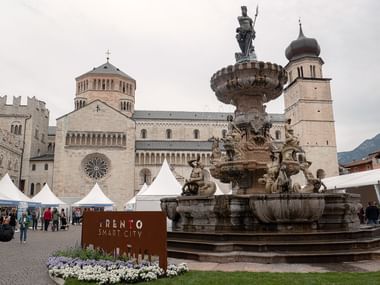 Der Neptunbrunnen in Trient steht auf einer Plaza mit der Kathedrale von Trient im Hintergrund.