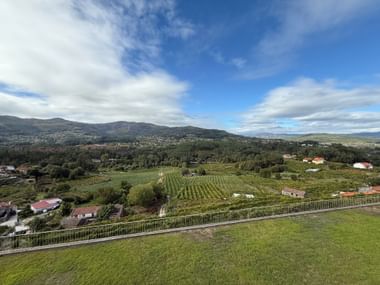 Panoramablick vom Weingut Soalheiro bei Monção mit Weinreben, grünen Hügeln, vereinzelten Häusern und Bergen unter blauem Himmel.