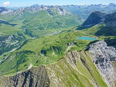 Blick auf Arlberg und die grüne Natur mit Bergsee aus der Vogelperspektive.