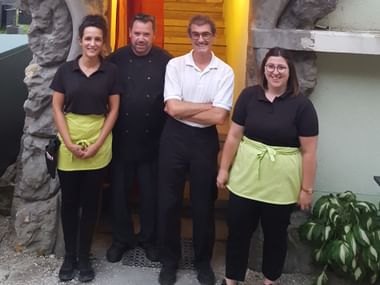 Quatre membres du personnel de cuisine du Restaurant de la Couronne à St. Ursanne posent ensemble en uniformes noirs et tabliers verts.
