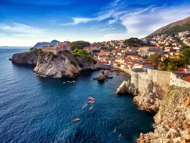 Luftaufnahme von Dubrovniks Altstadt mit Steinfestung auf Felsenklippen, historischen Stadtmauern und orangefarbenen Dächern an der Adria.