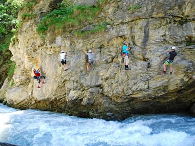 Escalade sur falaise calcaire au Tyrol Six grimpeurs avec casques et harnais escaladent une haute paroi calcaire au-dessus d'eaux blanches tumultueuses au Tyrol, Autriche.