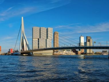 L'emblématique pont Erasme enjambe la Nieuwe Maas à Rotterdam avec l'horizon urbain moderne et ses gratte-ciel en arrière-plan.