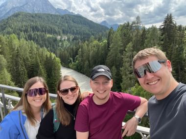 Vier Freunde lächeln auf einer Brücke über dem Fluss