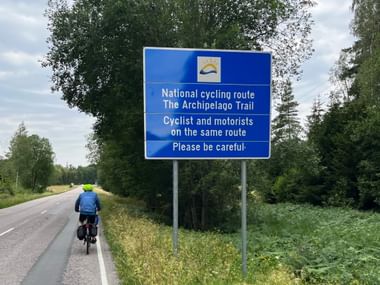 EIn Fahrradfahrer fährt auf einer asphaltierten Strasse entlang der National Cycling Route The Archipelago Trail von Turku nach Nauvo in Finnland