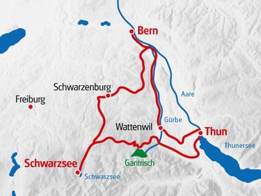 Relief map showing a red gravel cycling route connecting Bern, Schwarzenburg, Schwarzsee, Gantrisch, Wattenwil, and Thun with blue rivers and lakes.