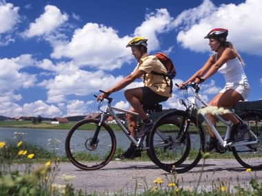 Deux cyclistes passent à côté d'un lac dans le Jura.