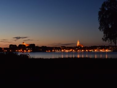 Die Beleuchtete Stadt am Seeufer in der Abenddämmerung. Die lichter spiegeln sich im See.