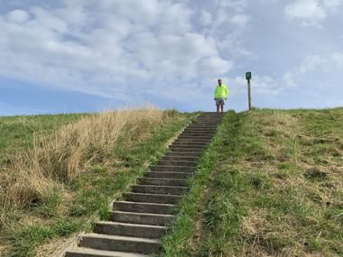 Sicht auf eine Treppe die auf einen Deich führt.