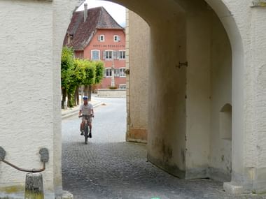 Ein Velofahrer fährt durch ein Tor in St-Ursanne.
