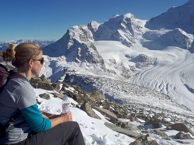 Eine Frau macht eine Pause im Schnee in den Bergen.