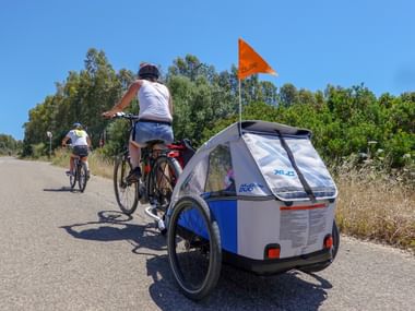 Zwei Radfahrer auf einer Strasse Sardiniens mit Kinderanhänger