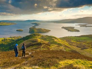 Zwei Wanderer betrachten den See Loch Lomond in Schottland