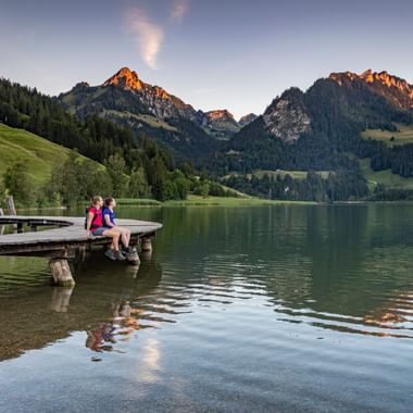 Zwei Wanderer sitzen auf einem Steg am Schwarzsee.