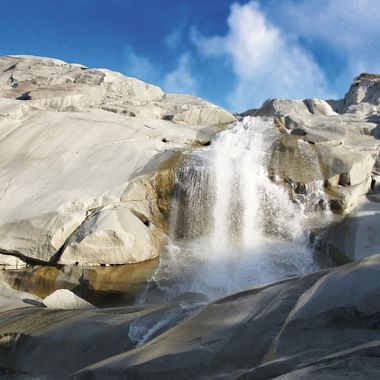 Ein Wasserfall stürzt einer Felswand hinunter an der Rhonequelle.