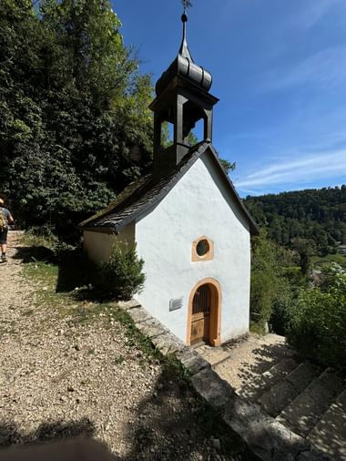 Die Einsiedelei von Saint-Ursanne liegt gut sichtbar im Grünen oberhalb der Stadt.