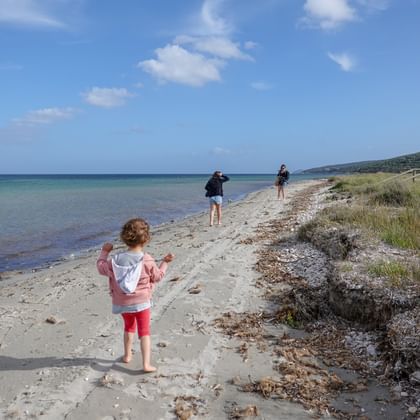Zwei Frauen und ein Kind befinden sich auf einem kleinen Strand auf Sardinien.