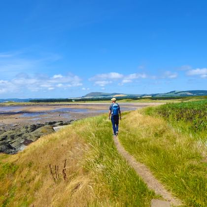 Wanderer bestaunt die malerische Landschaft am Fife Coastal Path