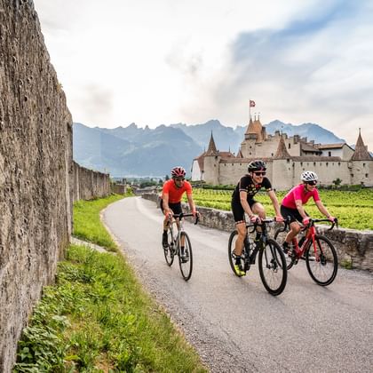 Drei Velofahrer fahren in Aigle vor einem Schloss vorbei auf der Velotour von Eurotrek.