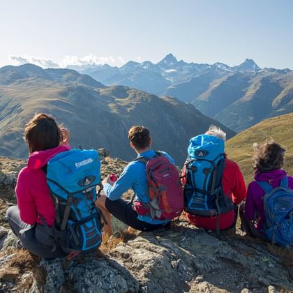 Vier Wanderer machen eine Pause auf einem Berg mit schönem Panorama.