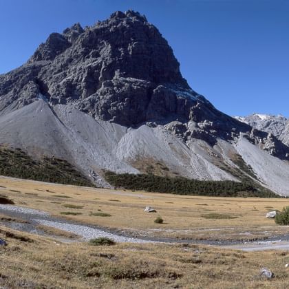 Zwei Biker fahren an den Bündner Bergen, auf einem schmalen Natursteinweg, vorbei.