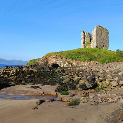 Eine Burgruine steht am Strand in Irland