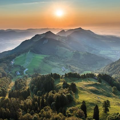 Atemberaubender Sonnenaufgang auf dem Weissenstein der den Hommel am Horizont in ein zartes orange färbt und den Berg und die Hügel in verschiedene grüntöne versetzt