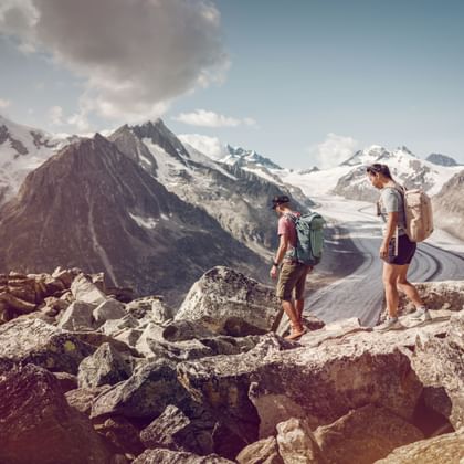 Ein Paar befindet sich auf dem Aletsch Panoramaweg direkt vor dem Aletschgletscher.