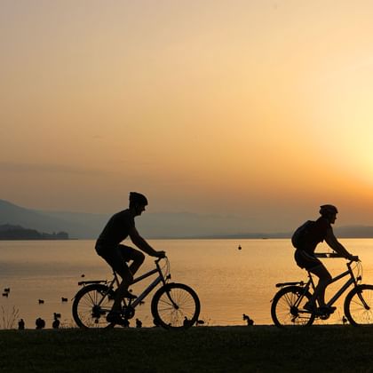 Velofahrer vor einem See im Sonnenuntergang