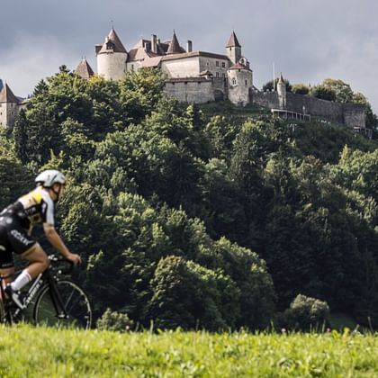 Radfahrer vor einem dicht bewaldeten Hügel mit Schloss