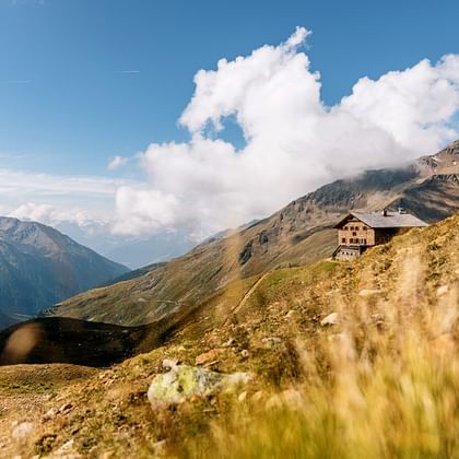 Die Sesvenna-Hütte und im Vordergrund eine Alpwiese im Gebirge.