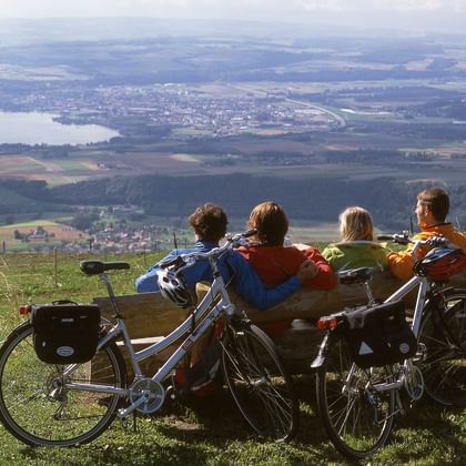 Quatre cyclistes assis sur un banc lors d'une pause, avec vue sur la vallée.