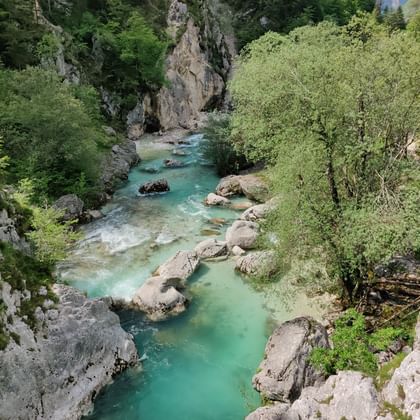 Türkisfarbener Fluss von oben fotografiert. Umgeben von Felsen und Bäumen.