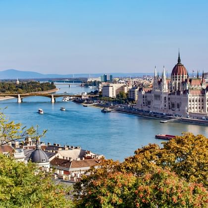 Panoramablick auf Budapests Stadtteil Pest mit dem ungarischen Parlamentsgebäude und seiner markanten Kuppel entlang der Donau mit Brücke.