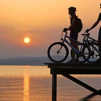 Des cyclistes profitent du coucher de soleil. Itinéraire sur l'Aar. Vacances à vélo avec Eurotrek.