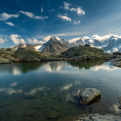 Crystal-clear mountain lake with a view of snowy peaks and a fantastic interplay of clouds.